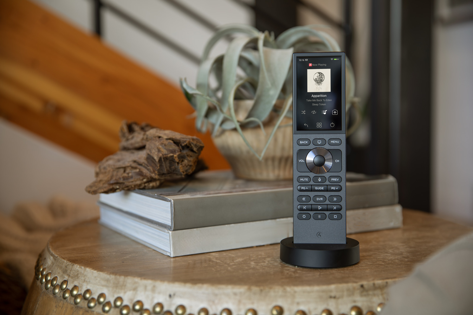 A Control4 remote in its charging dock on a living-room side table