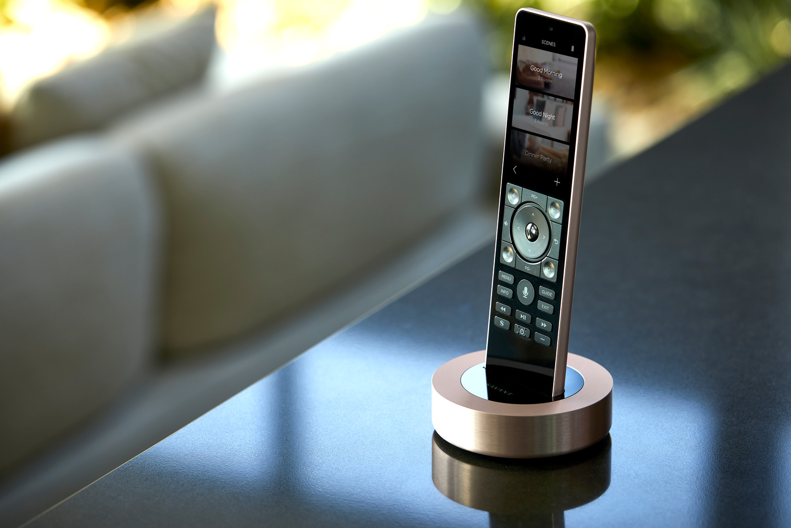 A Savant remote in its charging dock beside a sofa