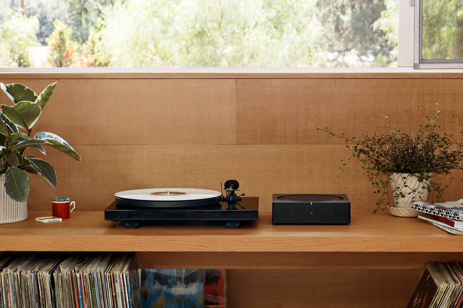 An audio amplifier and turntable on a low cabinet in a wood-paneled room