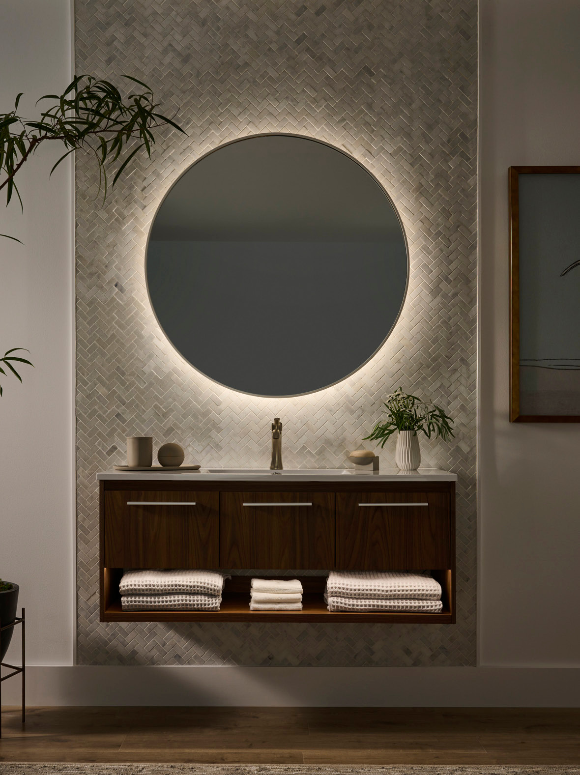 A bathroom vanity and round mirror in a cooler white-light setting