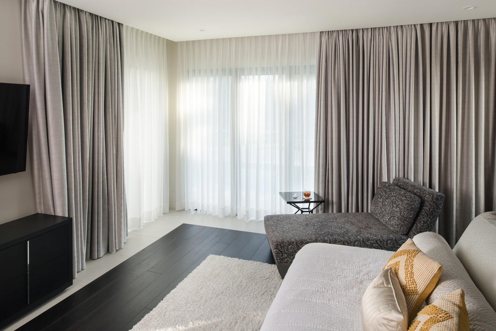 Floor-length drapery and sheer curtains layered around a bedroom sitting area