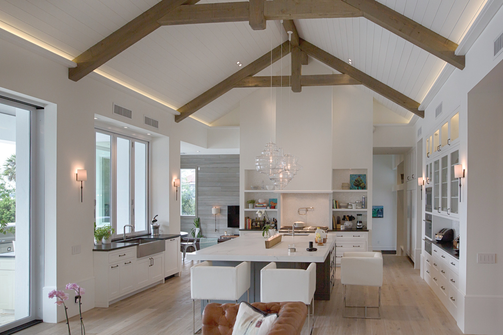 A kitchen with layers of light across the island, walls and exposed ceiling beams