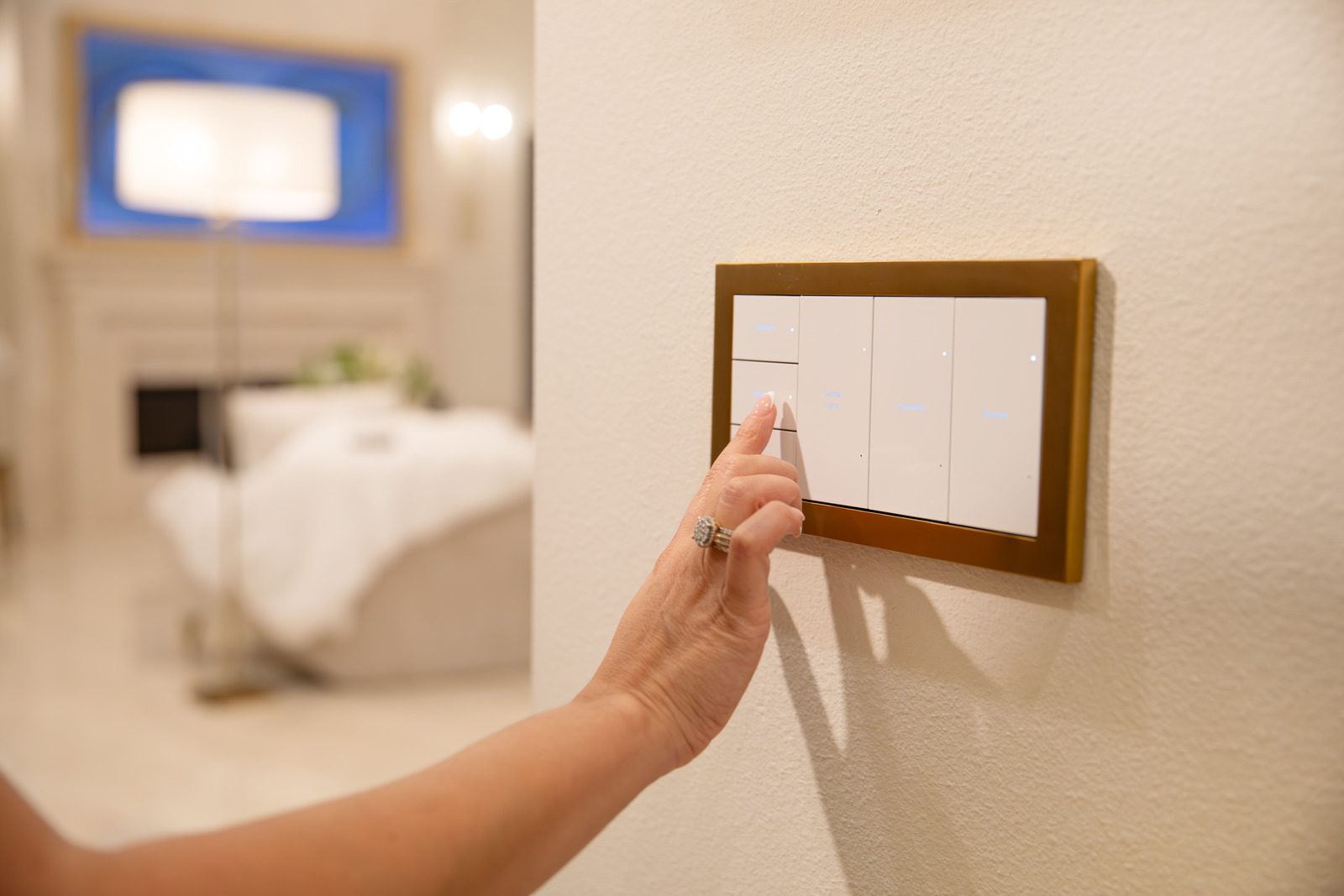 A person pressing a Control4 wall control beside a softly lit room
