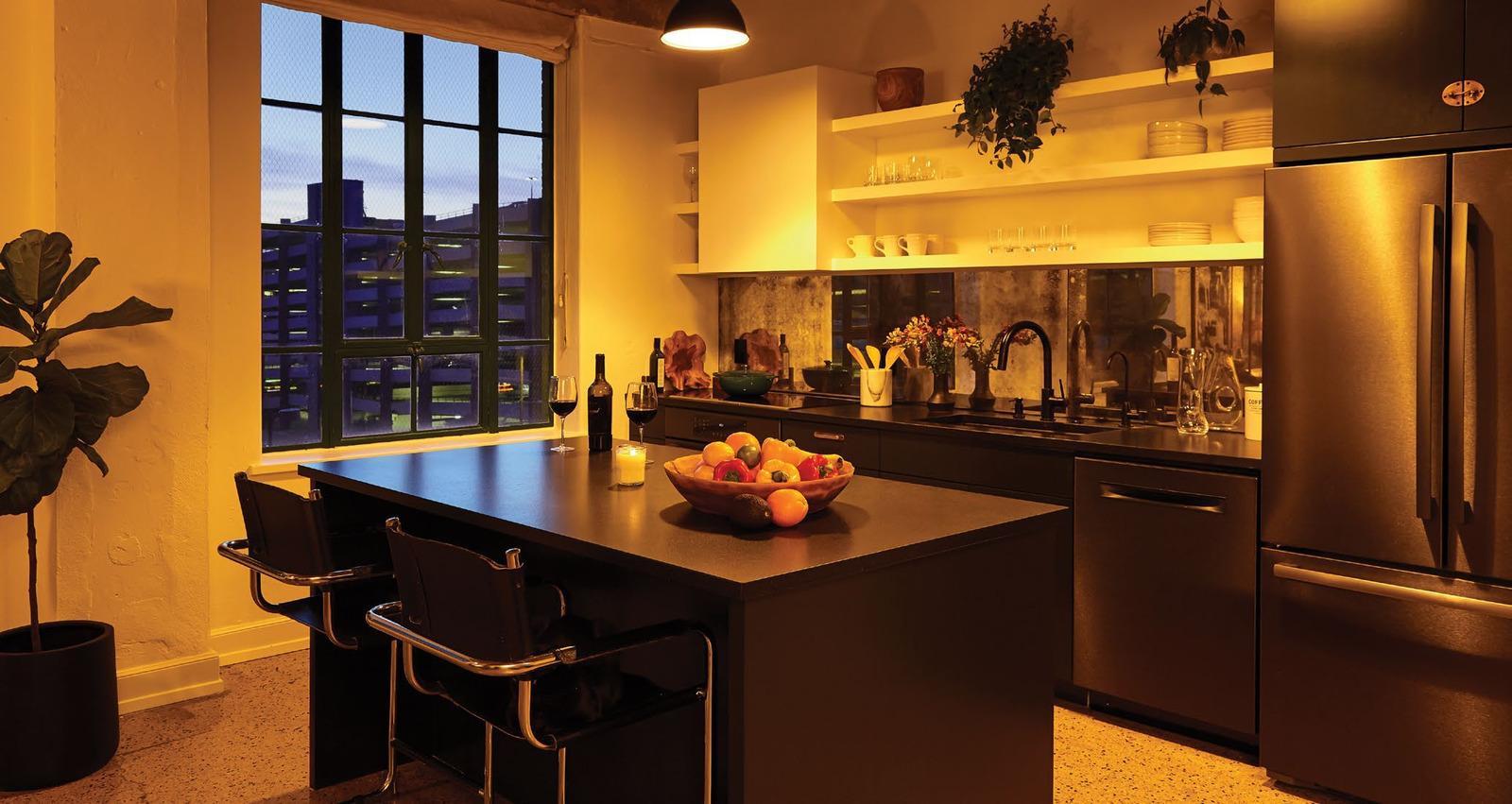 The Austin loft kitchen in a warm evening setting with illuminated shelves and pendant lights