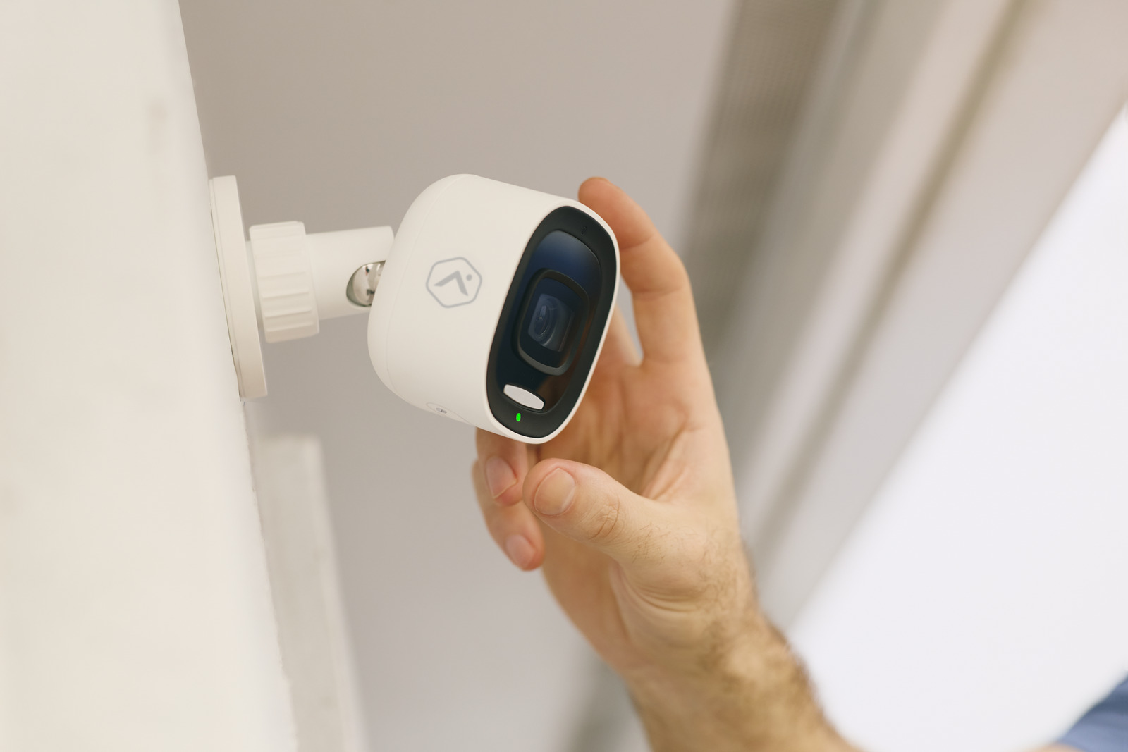 An installer positions an Alarm.com outdoor camera beneath an eave